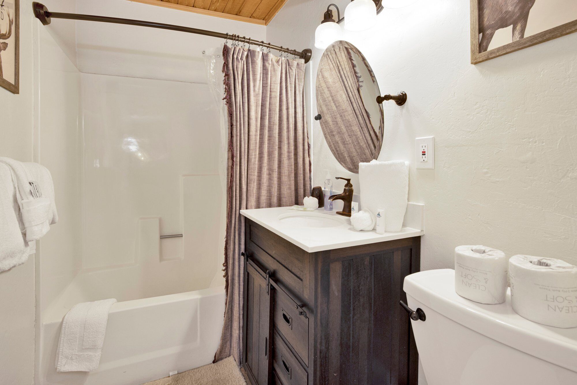 Ein Badezimmer mit Dusche, Waschbecken mit Spiegel, Toilette und Handtuchhalter.