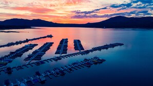 Una marina con numerose imbarcazioni ormeggiate in acque calme, circondata da colline.