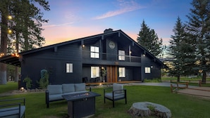A modern two-story house with a dark exterior, a fire pit, outdoor seating, and a well-maintained lawn. - THE Ranch House #2501 (Big Bear City)
