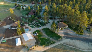 An aerial view of a residential area with houses, a dirt road, and a green space with a tent. - THE Ranch House #2501 (Big Bear City)