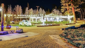 A well-lit outdoor area with a building, trees, and a paved path. - THE Ranch House #2501 (Big Bear City)