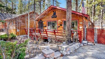 Set amidst the forest, this cabin features a porch with a stone pathway and a small deck.