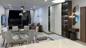 A modern living room with a glass dining table, comfortable seating, and a large window. - DongDong Apartment in Sunwah Pearl (Ho Chi Minh City)