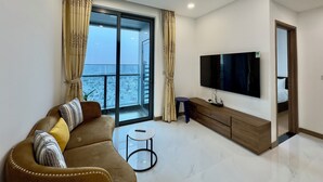A modern living room with a large window, a sofa, a TV, and a small table. - DongDong Apartment in Sunwah Pearl (Ho Chi Minh City)
