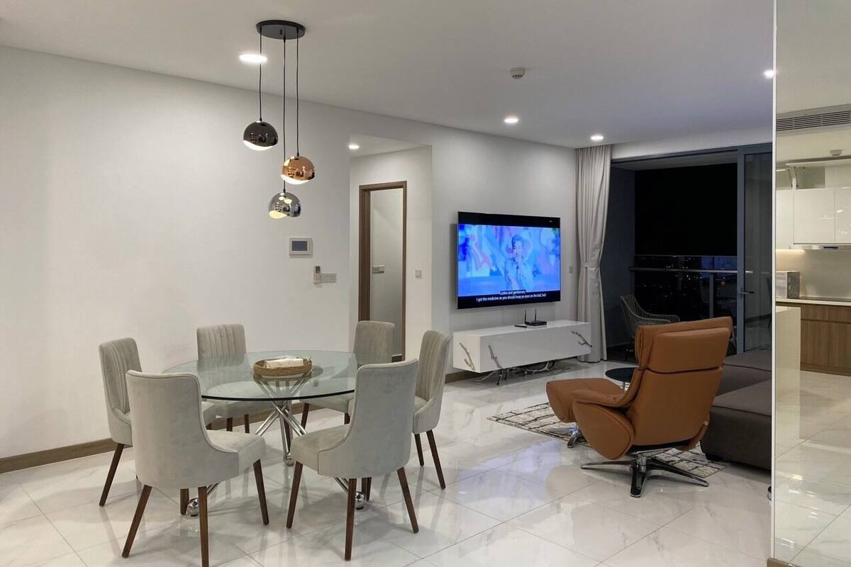 Un salon moderne avec une table à manger en verre, des sièges confortables, un téléviseur à écran plat et un balcon avec vue.