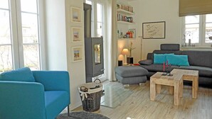 Un salon avec un canapé bleu, un pouf gris, une table basse en bois et une cheminée.