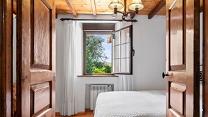 Une chambre avec un plafond en bois, une fenêtre avec des rideaux, un radiateur et un lit.