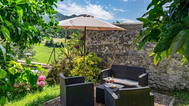 Un espace extérieur aménagé avec des meubles en osier, une table et un parasol.