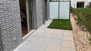 A modern building with a brick facade, a glass door entrance, and a small grassy area with mulch.