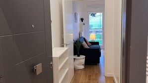 A hallway with a dark grey wardrobe, white shelving units, and a wooden floor.
