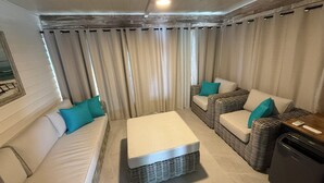 A room with a sofa, a chair, a small table, and a trash bin. - Venice Villas #7 (Venice)