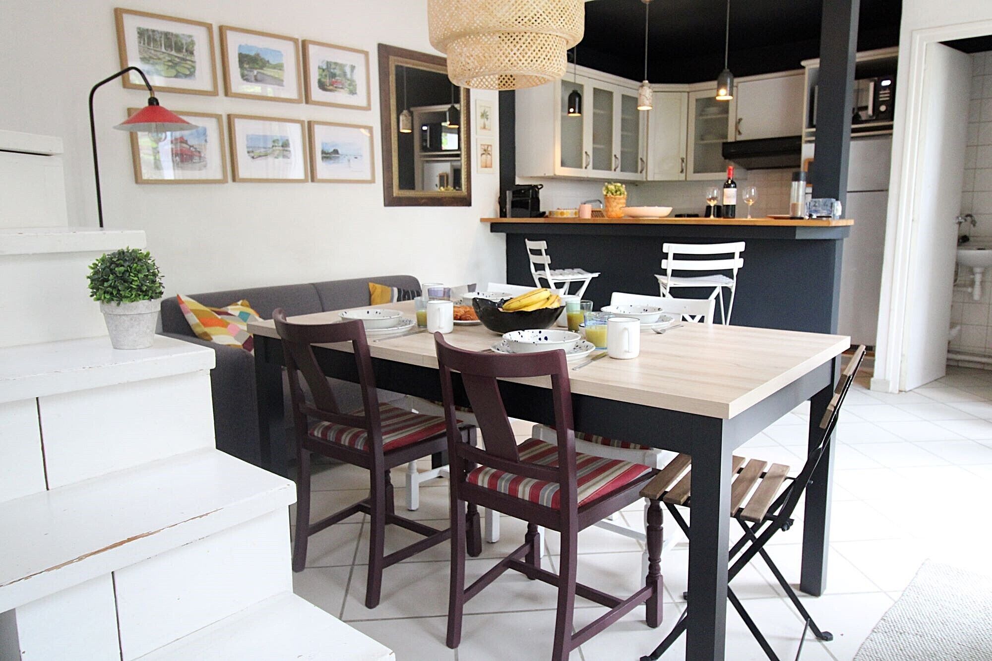 Une cuisine moderne avec un coin repas, comprenant une table en bois, des chaises et un luminaire suspendu.