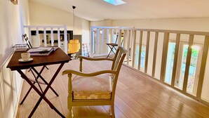Uma varanda com piso de madeira, mesa de jantar com cadeiras e vista para o exterior.
