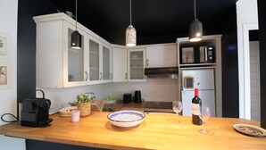 Cozinha com armários brancos, bancada de madeira, micro-ondas, torradeira e uma garrafa de vinho.