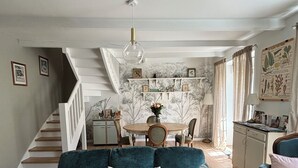 Ein Wohnzimmer mit einem dunkelgrünen Sofa, einem Holzesstisch und einer Treppe, die zu einer anderen Ebene führt.