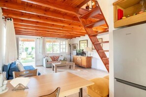 A cozy cabin interior with a wooden staircase, a dining area, and a kitchen.