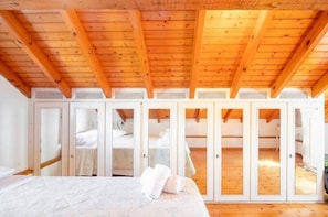 A bedroom with a wooden ceiling, a bed, and a wardrobe with mirrored doors.