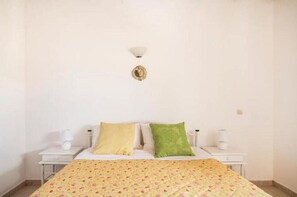 Une chambre à coucher comprenant un lit, deux tables de chevet, une petite table, un luminaire fixé au mur et un élément décoratif mural.
