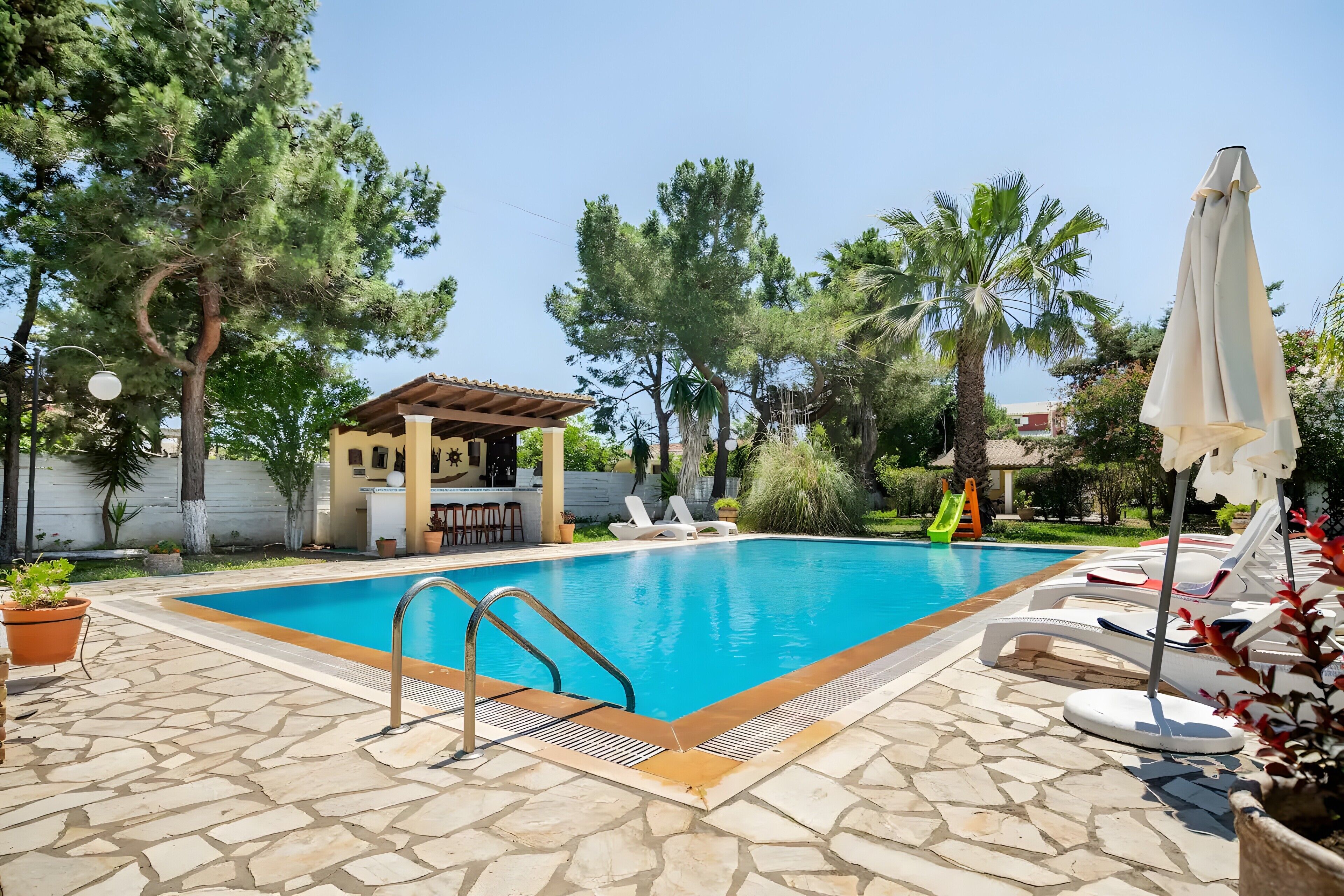 A swimming pool with lounge chairs and a pergola.