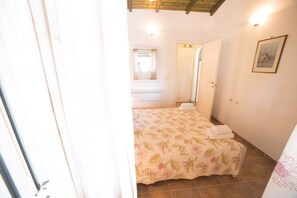 Une chambre à coucher avec un lit, une fenêtre avec des rideaux, une porte et un tableau accroché au mur.