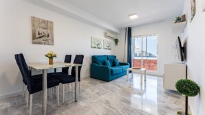 Una sala de estar moderna con una mesa de comedor, un sofá azul y obras de arte en las paredes.