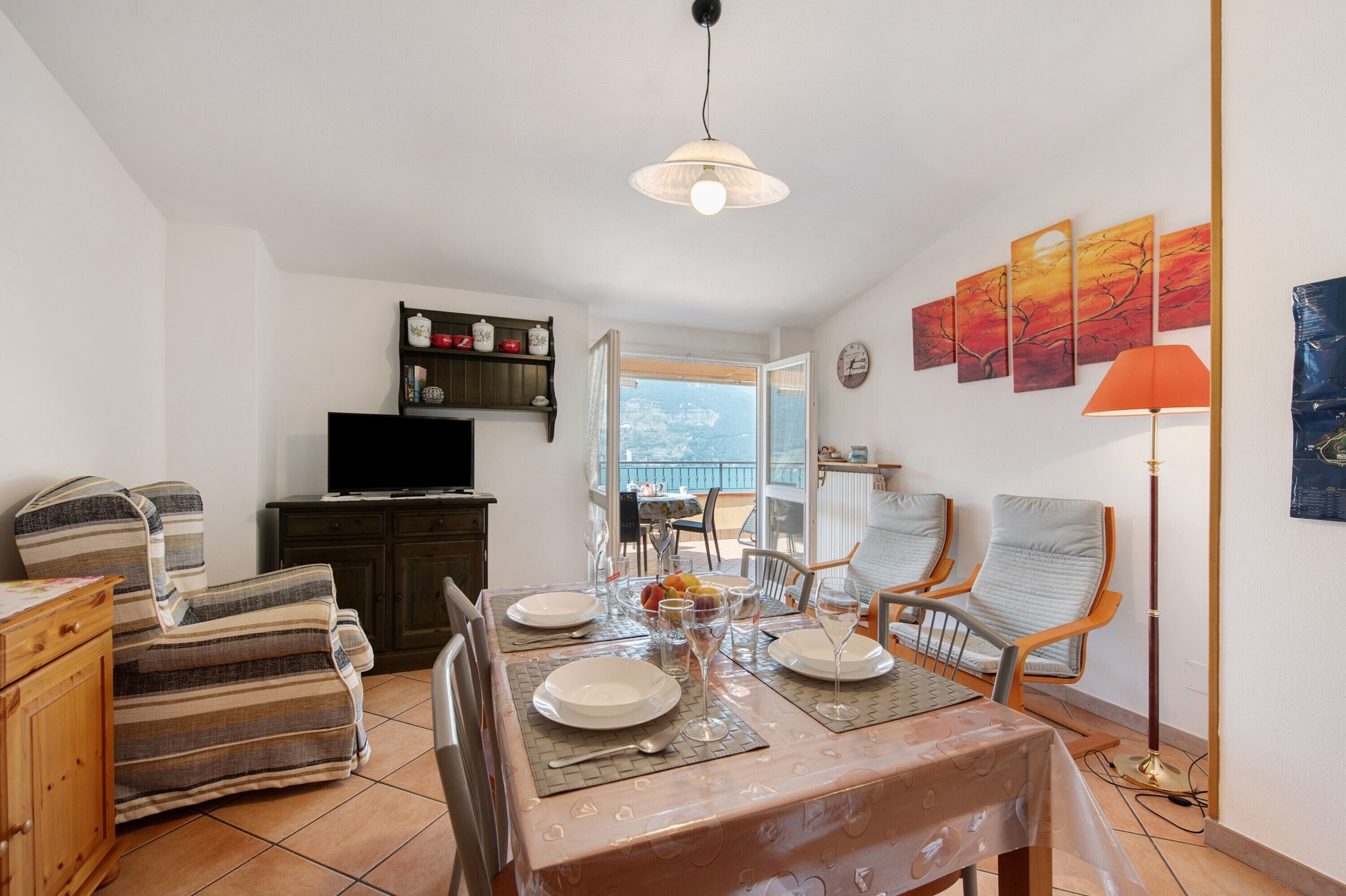 A dining area with a table set for four, a television, and a view of the outdoors.