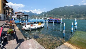 A waterfront dock with boats, a covered seating area, and a mountainous backdrop.