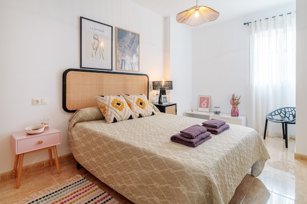 A bedroom with a bed, bedside tables, a chair, and artwork on the wall.
