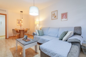 A modern living room with a sofa, a dining table, chairs, and a pendant light.