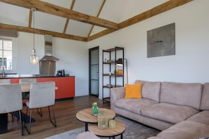 A modern living space with a kitchen, dining area, and a large sofa. - Villa in Someren Near Golf Course (Someren)