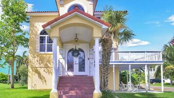 A two-story building with a yellow facade, a red-tiled roof, and a white porch.