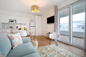 Un salon moderne comprenant un canapé, un coin repas, une cuisine et un balcon avec vue.