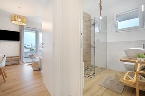 Une salle de bain moderne avec une douche en verre, un lavabo blanc et un meuble-lavabo en bois.