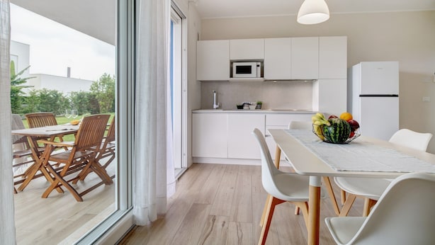 A modern kitchen with white cabinets, a microwave, and a refrigerator. - Apartment 'Deluxe 5' with Shared Garden, Wi-Fi and Air Conditioning (Jesolo)