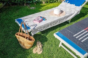A sunbed with a patterned cover, a wicker basket, a pair of flip-flops, and a blue lounge chair. - Studio Apartment 'Open Space 1' with Shared Garden, Wi-Fi and Air Conditioning (Jesolo)