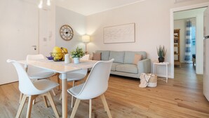 Un salon moderne comprenant une table à manger, des chaises, un canapé, une lampe, une horloge et une plante.