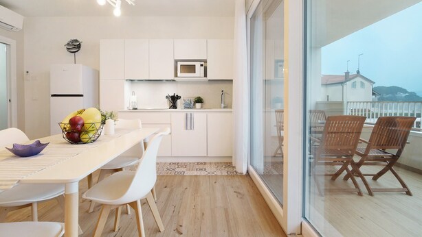 Une cuisine moderne avec des meubles blancs, un four à micro-ondes et un coin repas comprenant une table et des chaises.
