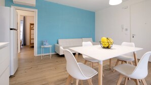 Eine moderne Küche mit weißen Schränken, einem weißen Esstisch mit vier Stühlen und einer blauen Akzentwand.