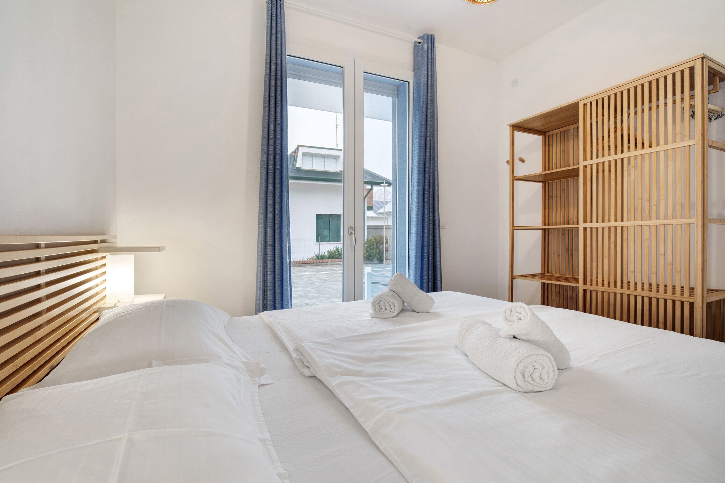 Une chambre d’hôtel avec un lit, une armoire en bois et une vue sur l’extérieur, visible à travers une porte vitrée.
