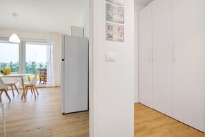 Eine moderne Küche mit weißen Schränken, einem Kühlschrank und einem Essbereich mit Tisch und Stühlen.
