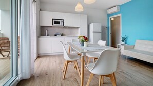 Une cuisine moderne avec des meubles blancs, une table à manger avec des chaises et des luminaires suspendus.