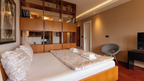 Een moderne slaapkamer met een groot bed, een houten garderobe, een bureau en een stoel.