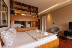 A modern bedroom with a large bed, a wooden wardrobe, a desk, and a chair. - Central Park Apartments (Belgrade)