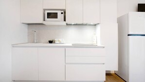 A modern kitchen with white cabinetry, a microwave, a sink, and a refrigerator. - Studio Apartment 'Open Space 2' with Shared Garden, Wi-Fi and Air Conditioning (Jesolo)