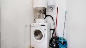 A compact laundry area with a front-loading washing machine, a hose, and a mop. - Studio Apartment 'Open Space 2' with Shared Garden, Wi-Fi and Air Conditioning (Jesolo)