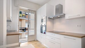 Una cocina moderna con armarios blancos, encimera de madera y electrodomésticos integrados.