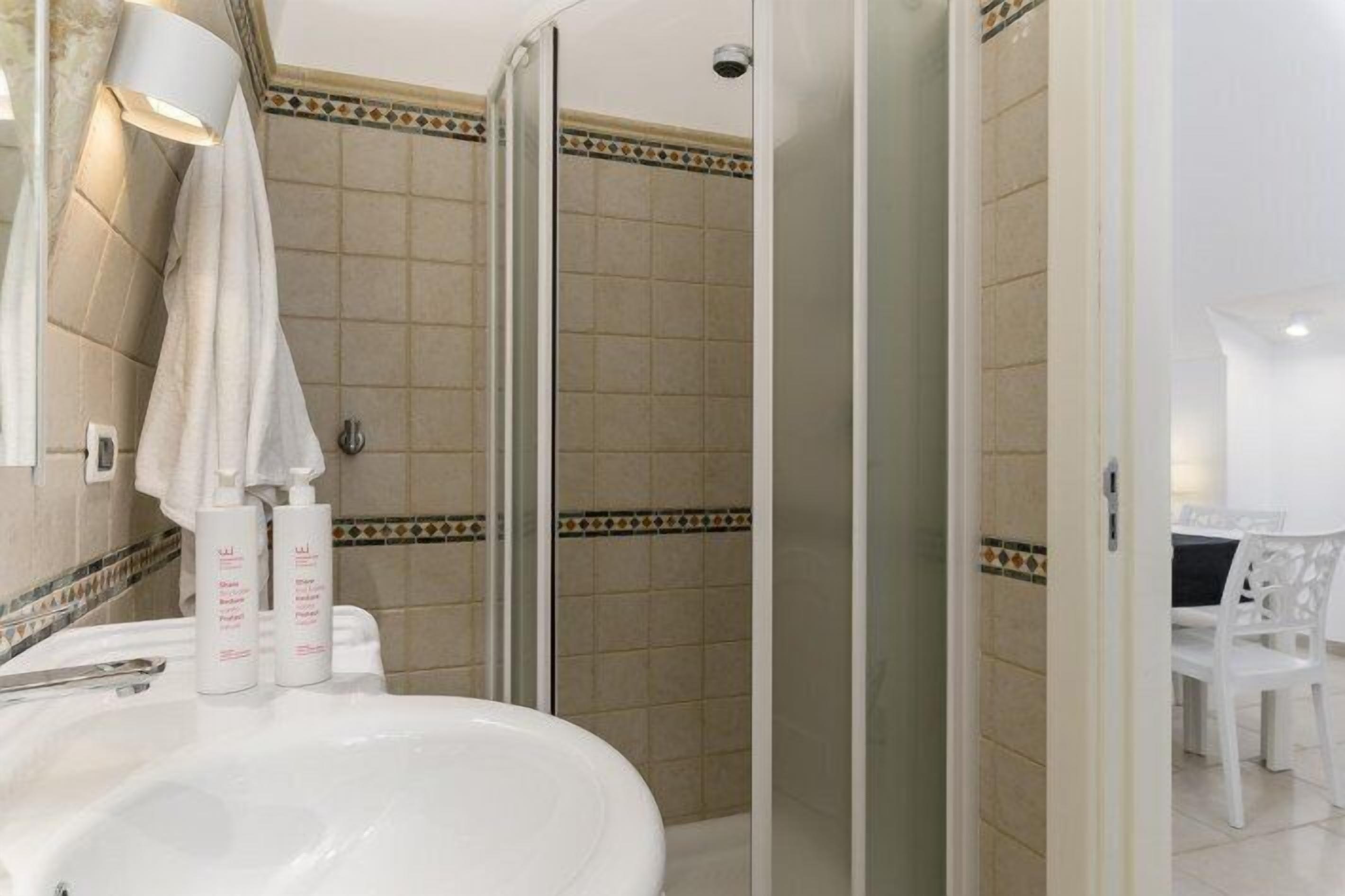 A bathroom with a shower, a sink with toiletries, and a mirror.