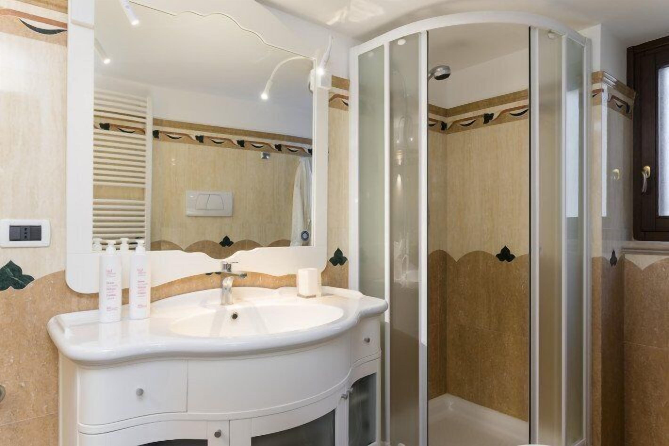 Une salle de bain avec un lavabo blanc, un miroir et une douche à parois de verre.