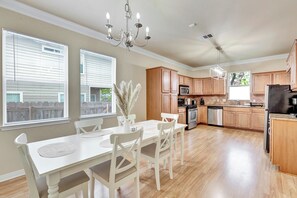 Enjoy cooking in the well-equipped kitchen with a central island, stainless steel appliances, and a dining area with a table and chairs.