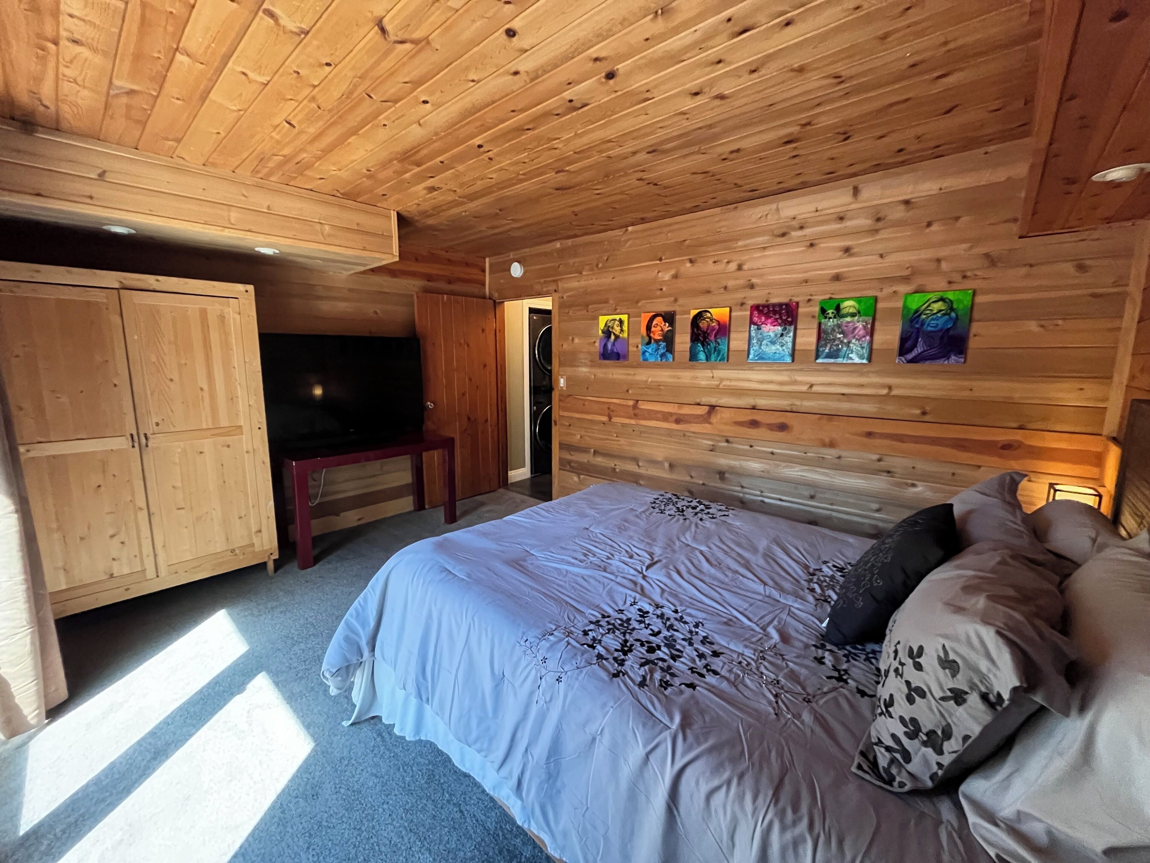 Ein Schlafzimmer mit Holzwänden, einem Bett, einem Fernseher und einem an der Wand befestigten Kunstwerk.